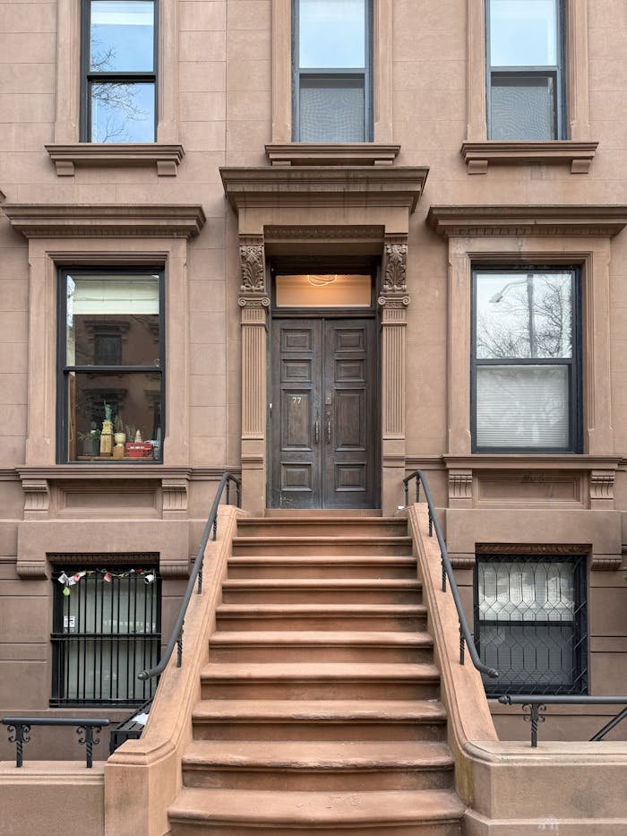 Traditional brownstone facade with iconic steps in New York City, capturing urban architectural charm.