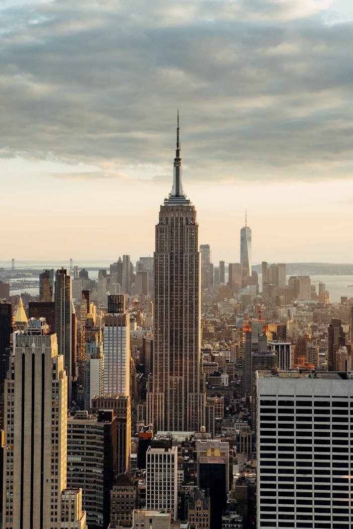 Iconic view of the Empire State Building amidst New York City's skyline at sunrise.