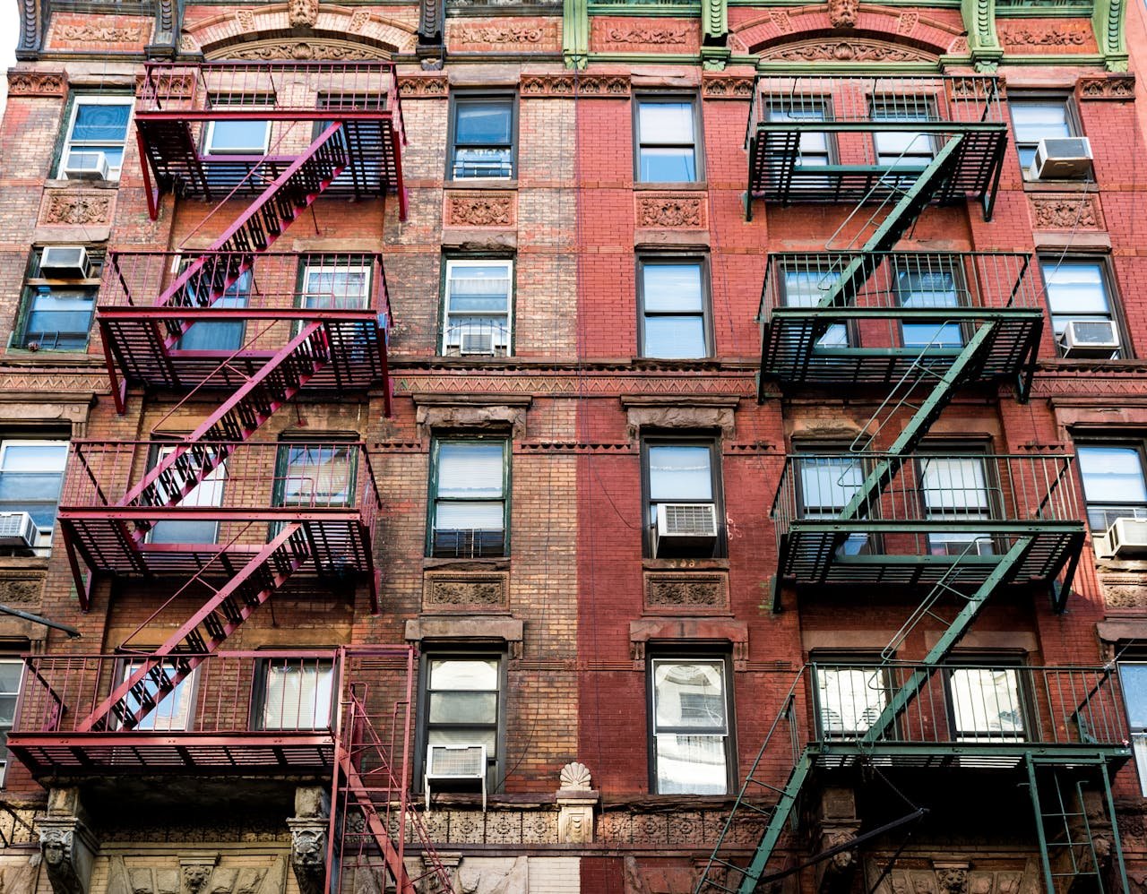 Colorful brick building facade with fire escapes in New York City, showcasing urban architecture and design.
